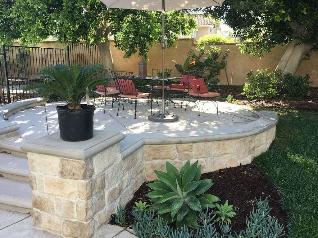 raised stone patio edging with plants and barkdust