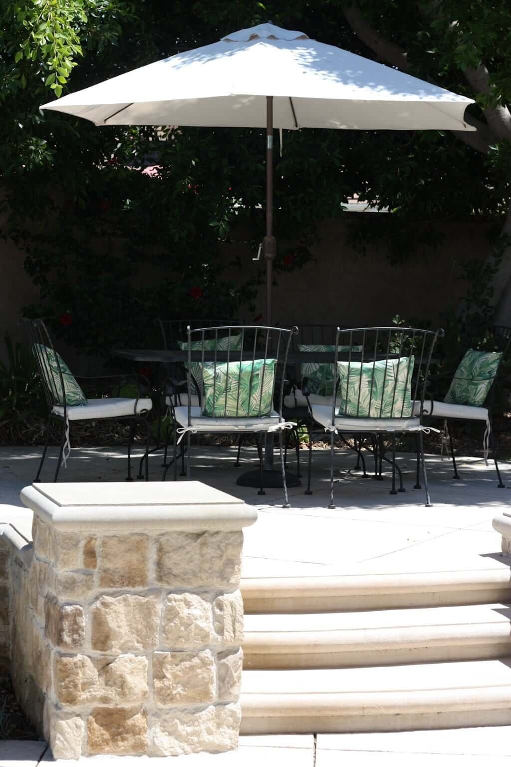 raised concrete patio with stone veneer retaining wall and outdoor dining area 