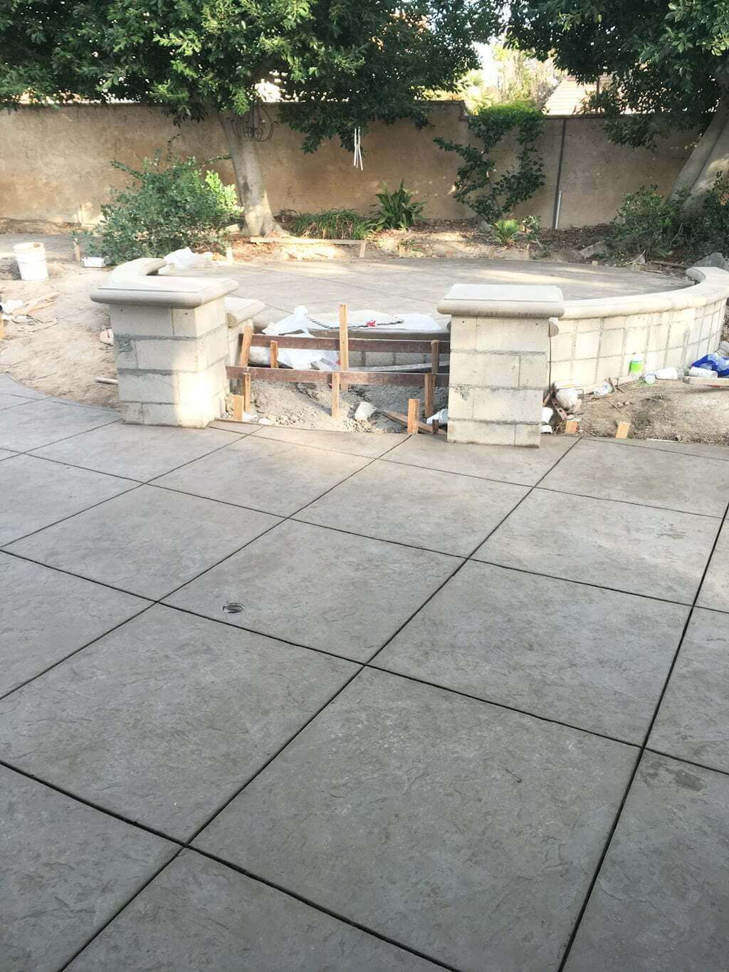 building a raised patio with retaining wall and concrete steps between two pillars with concrete bullnose caps