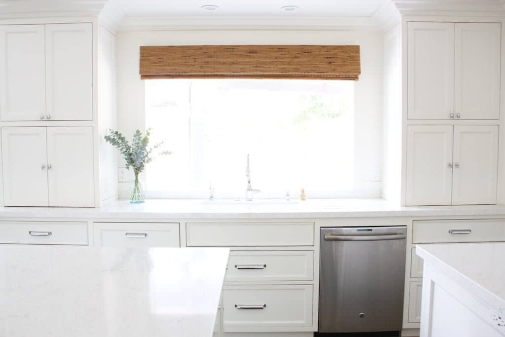 kitchen sink with cordless window shade above, and hidden countertop appliance cabinets to side