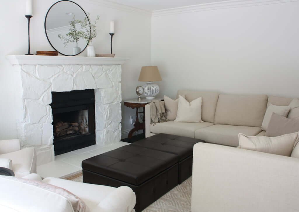 living room with sectional couch, fireplace, and two leather ottomans