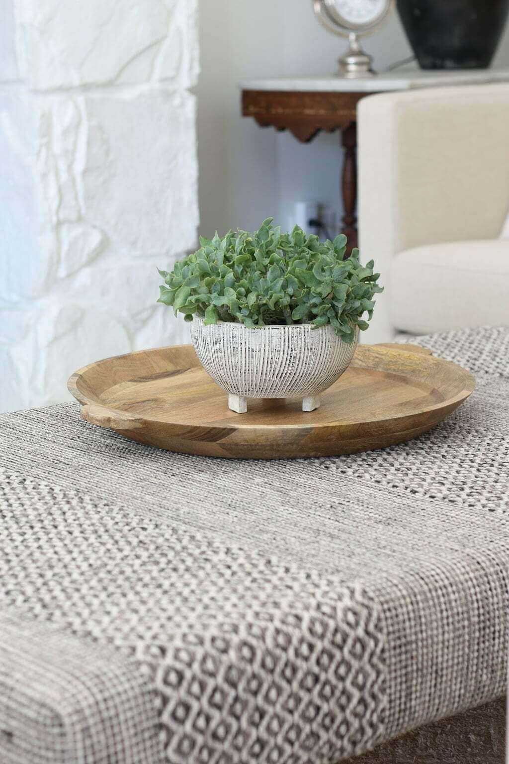 closeup of DIY rug covered ottoman with tray and plant on top like a coffee table