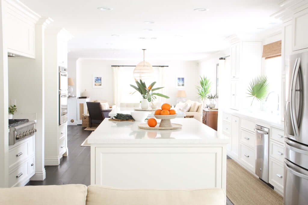 A timeless white kitchen with white quartz countertops, dark hardwood floors and quartz backsplash