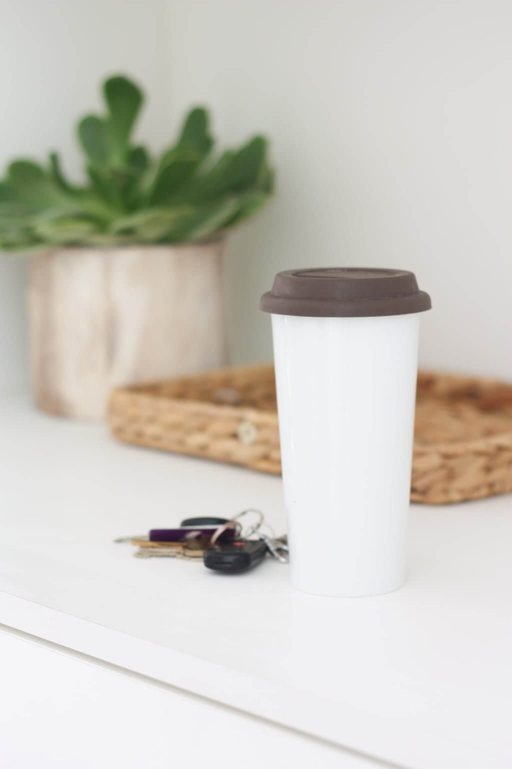 closeup of ceramic coffee cup and keys on entryway table drop zone