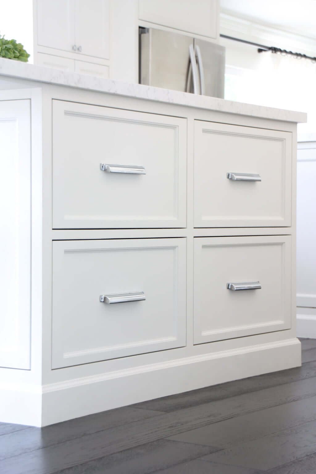 set of four extra-deep drawers in white kitchen island with dark wood floors