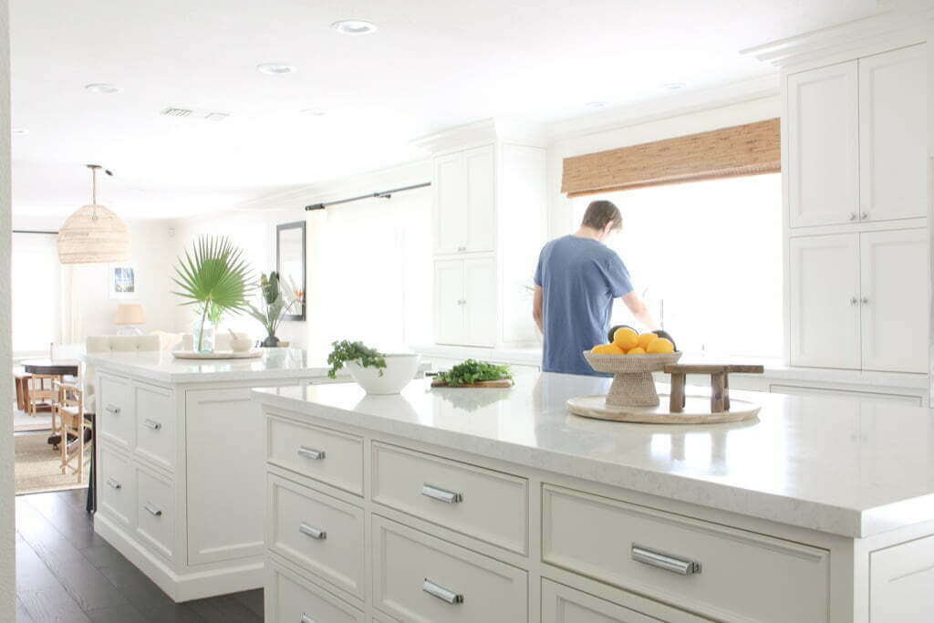 man standing at kitchen counter height raised at sink, with two quartz kitchen islands in foreground