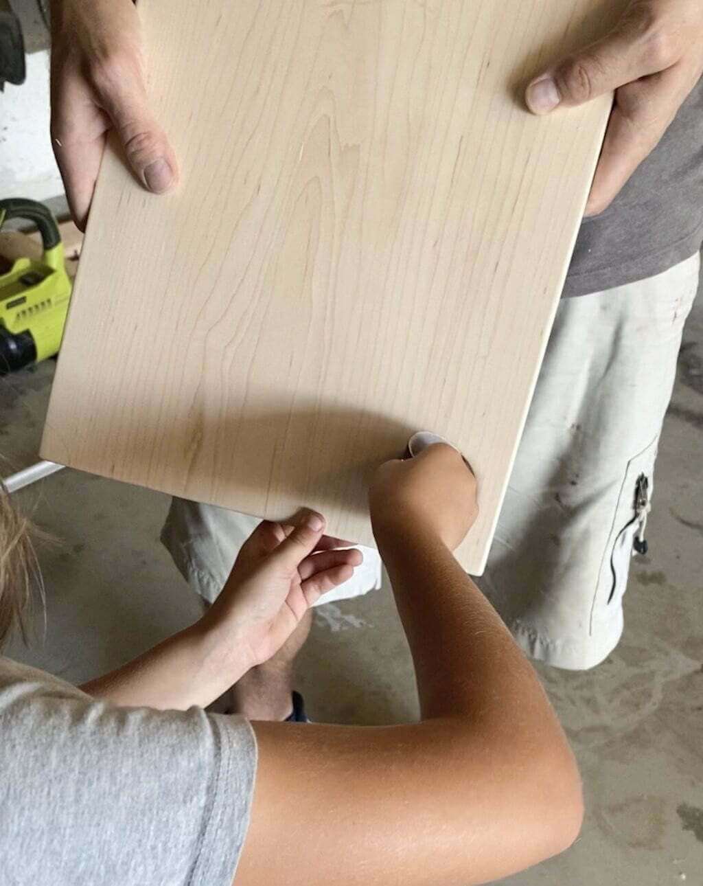 girl sanding hole in DIY cutting board