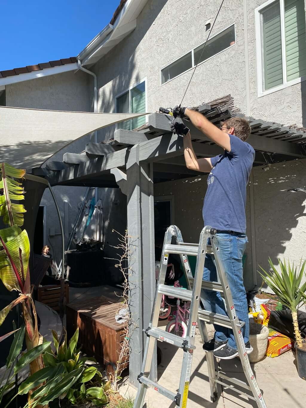 man installing backyard zipline without trees into an arbor post