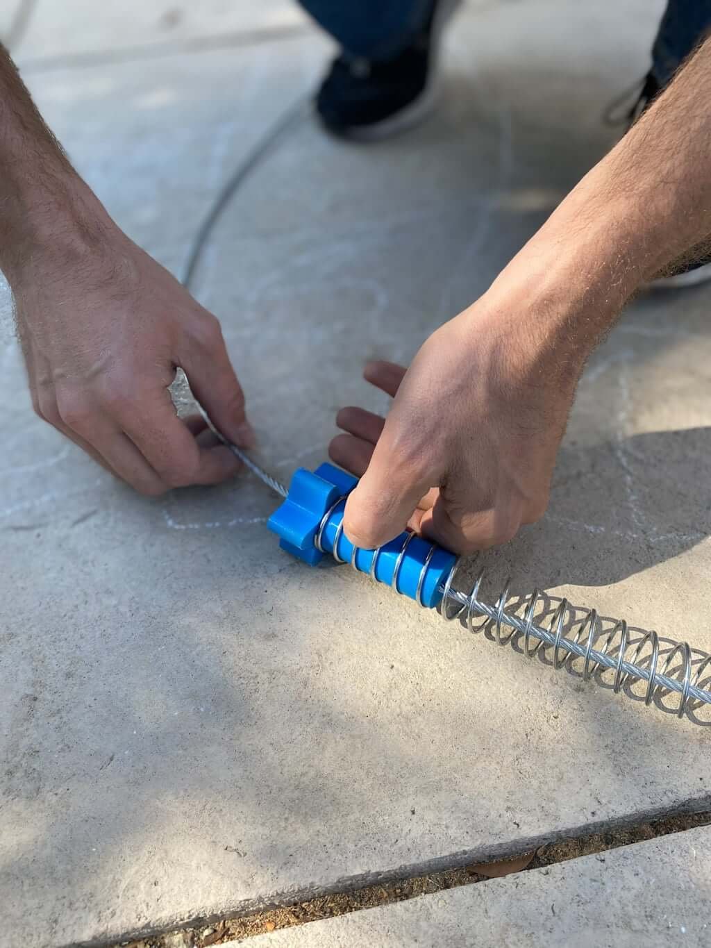 man's hands pulling zipline wire through to install