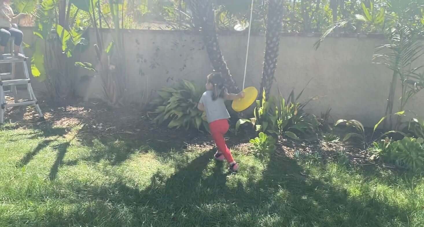 girl pulling backyard zipline seat back to ladder platform 