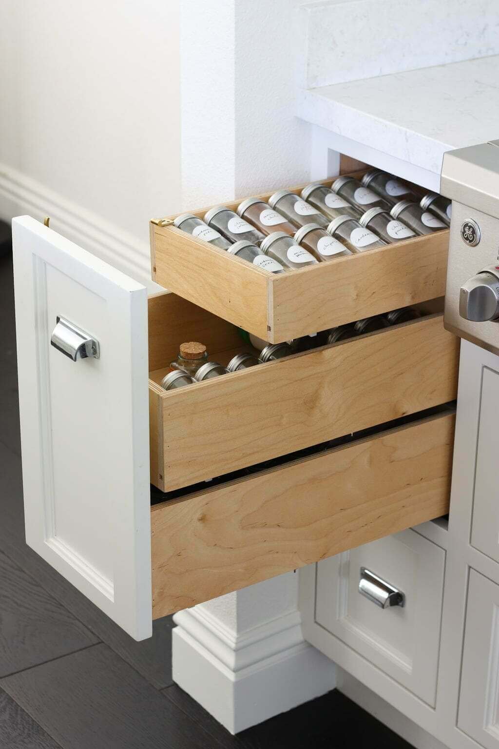 vertical pull out spice rack drawers with labeled spices organized inside