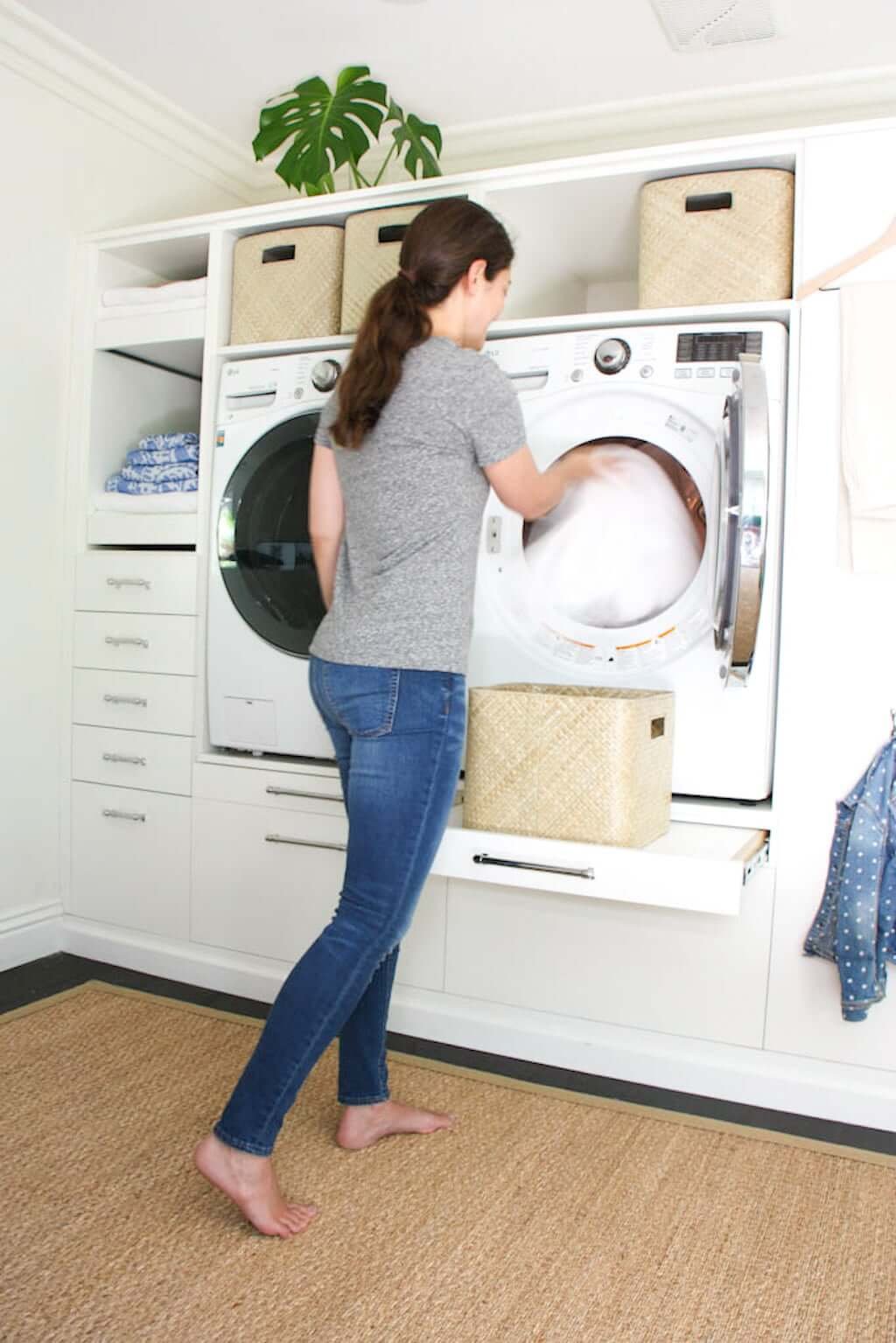 woman using laundry room makeover, pulling towels out of dryer into basket