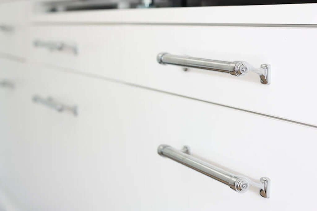 sliding shelf below washer and dryer in laundry room, with chrome handle