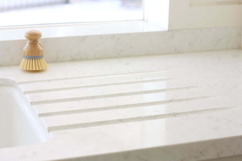 white quartz countertop with drainboard runnels next to sink