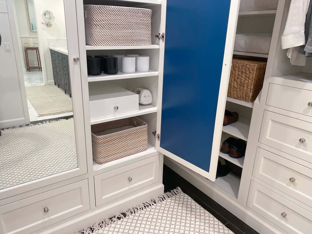 folding ironing board drawer, closed, in cabinet with baskets on shelves and mirrors on cabinet doors