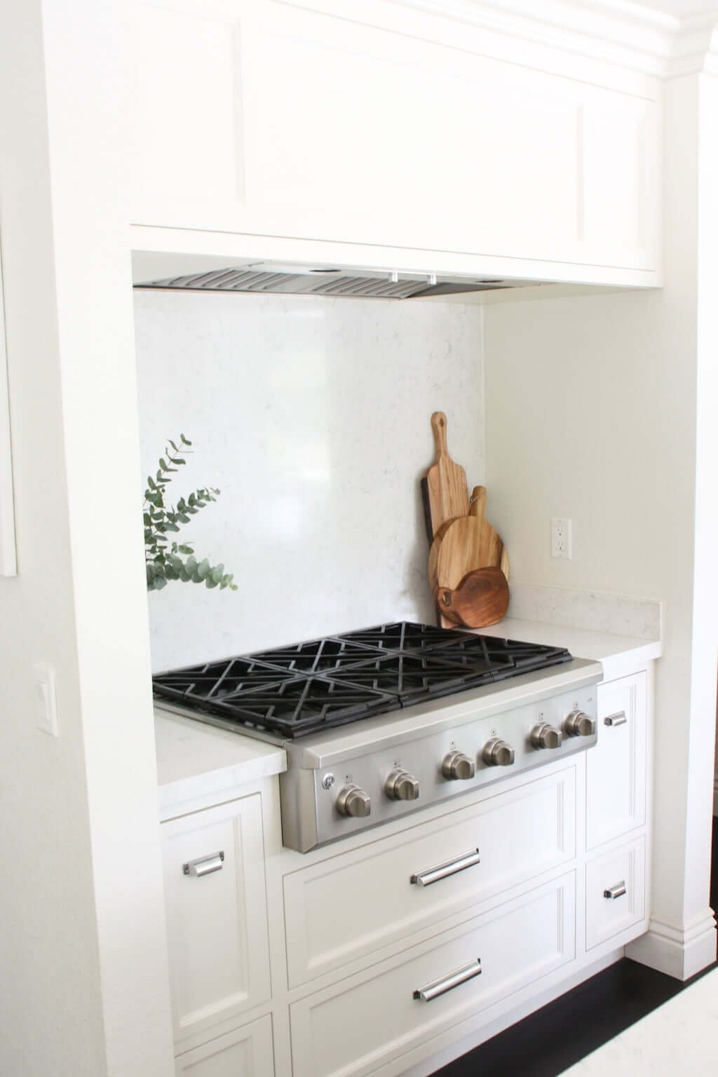 white quartz backsplash behind stove in white kitchen, white solid surface panels behind range