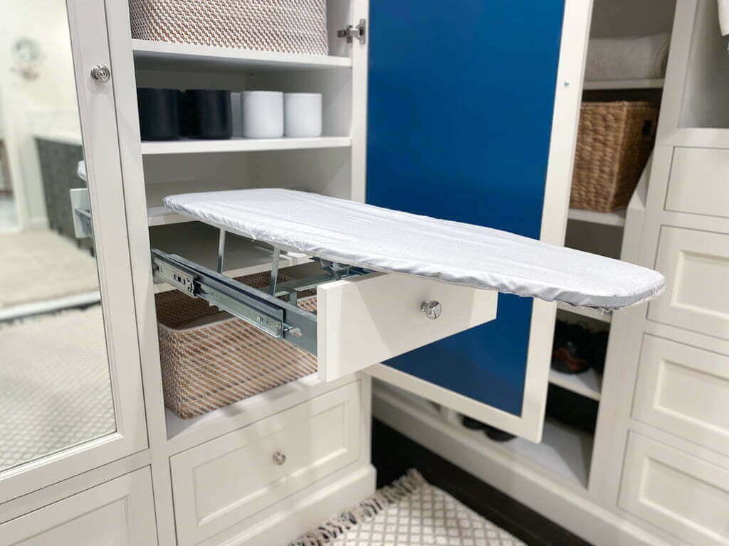 A folding pull-out ironing board stored within a closet.