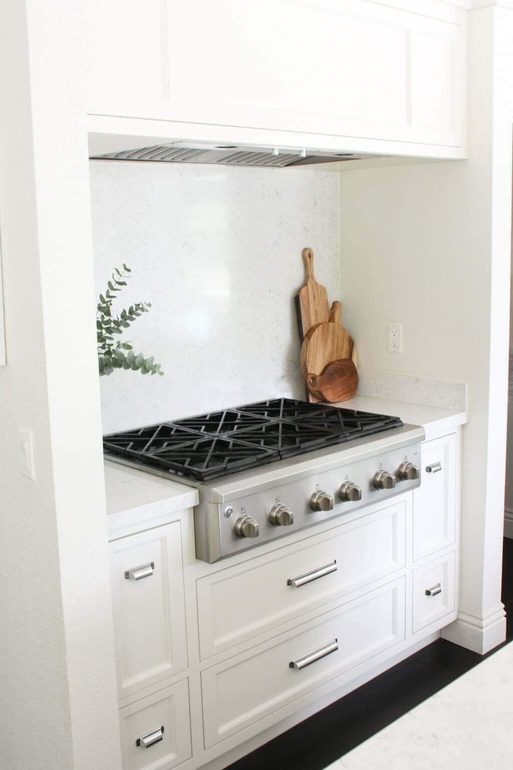 quartz backsplash behind stove in white kitchen, solid surface slab