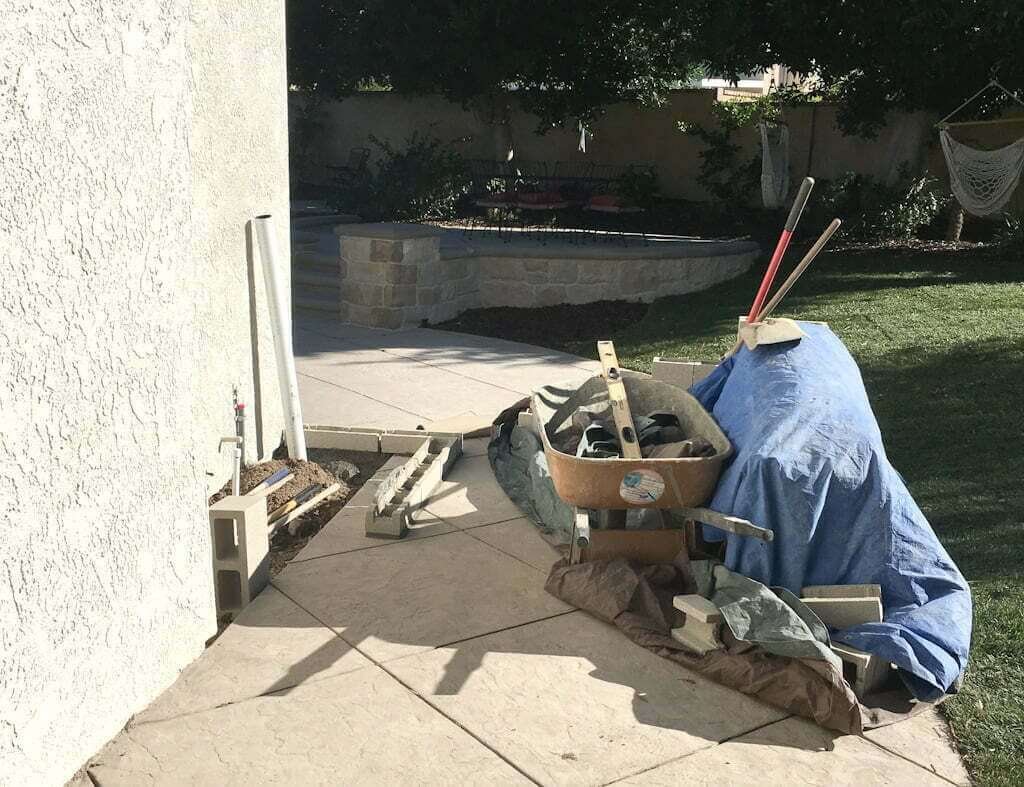 concrete and materials set out ready to build a small backyard kitchen along side of house