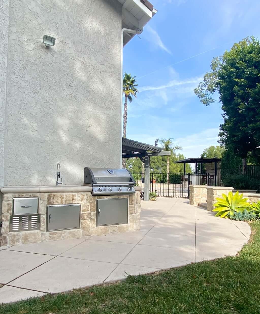 Backyard kitchen with outdoor built in grill, small outdoor kitchen sink, and stainless steel outdoor cabinets