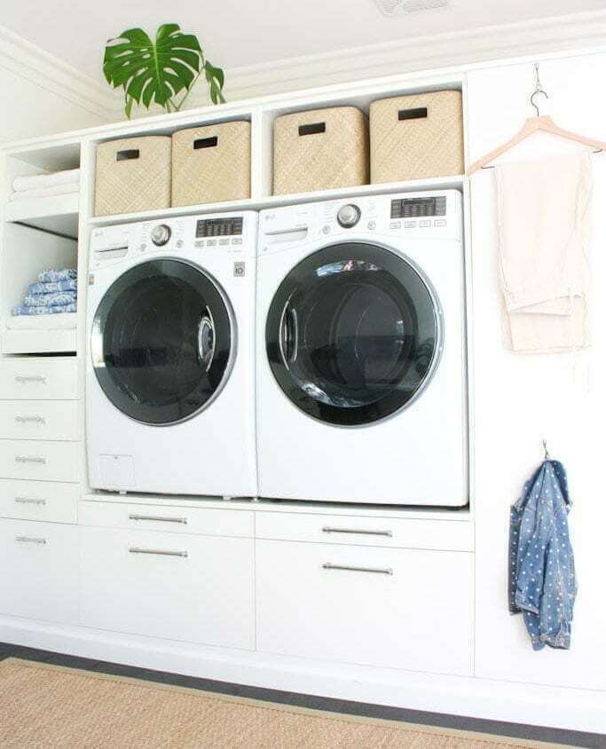 white laundry room decor with woven baskets, wooden hangers, open shelving, plants and drawers