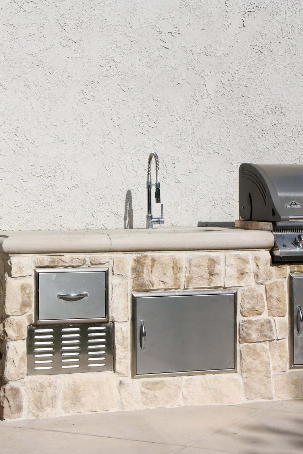 outdoor sink and stainless steel outdoor sink faucet next to BBQ in outdoor kitchen with stainless steel drawers