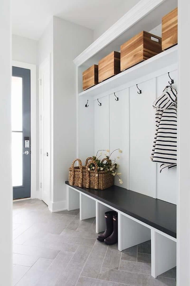 black and white entryway with mudroom bench with board and batten, cubbies, and herringbone tile