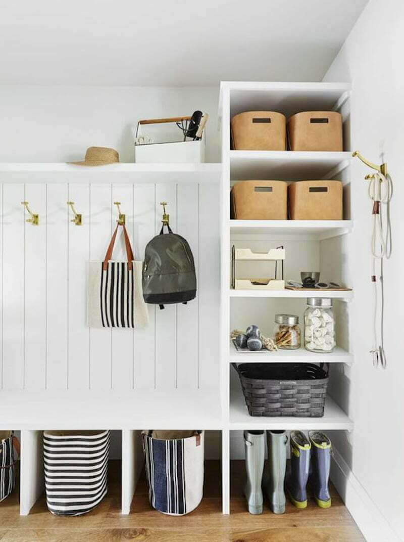 white entrayway bench with shelves, brass hooks, and shoe storage