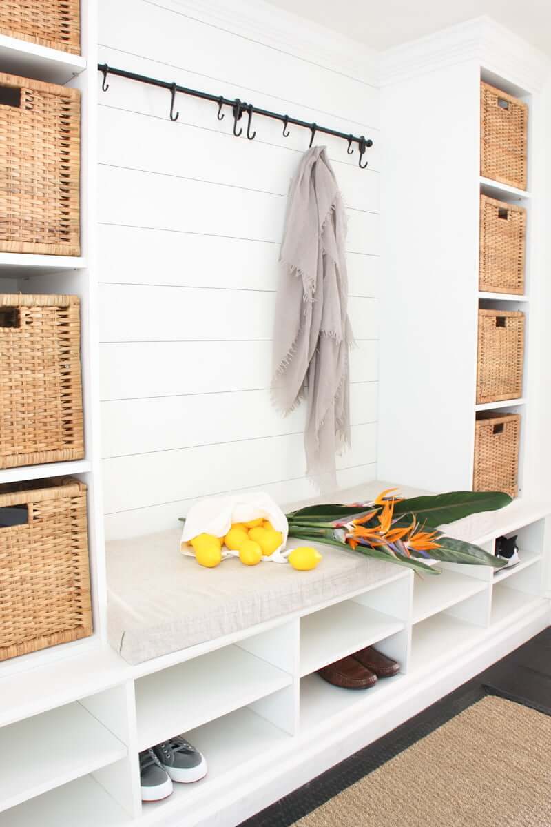 mudroom bench shiplap with cushion, shoe shelves, baskets on vertical shelves, horizontal beadboard walls, and black hooks