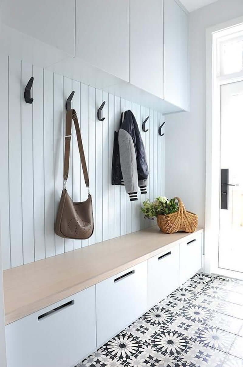 modern mudroom bench in entryway with shoe drawers, cement tile floors, modern hooks, and upper cabinets