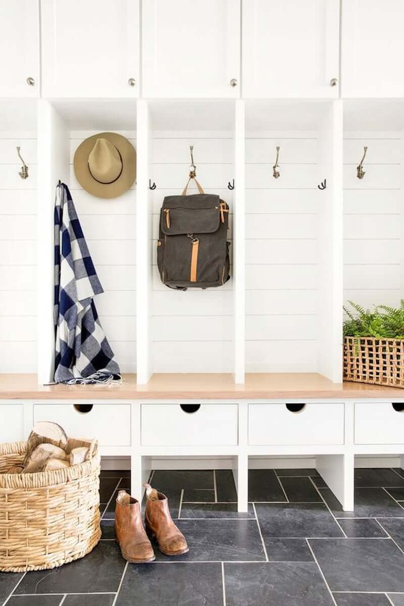 white mudroom bench with wood top, white drawers, cubbies and slate floor with white shiplap walls