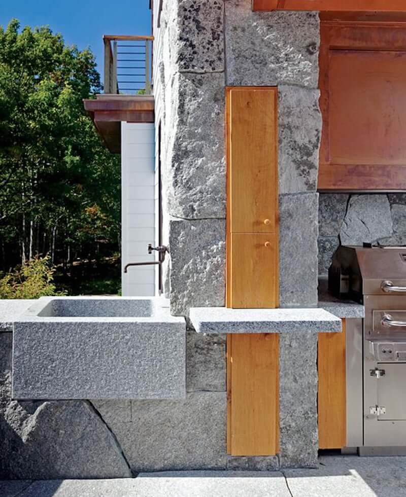 chiseled stone garden sink with faucet and outdoor kitchen along side of a house