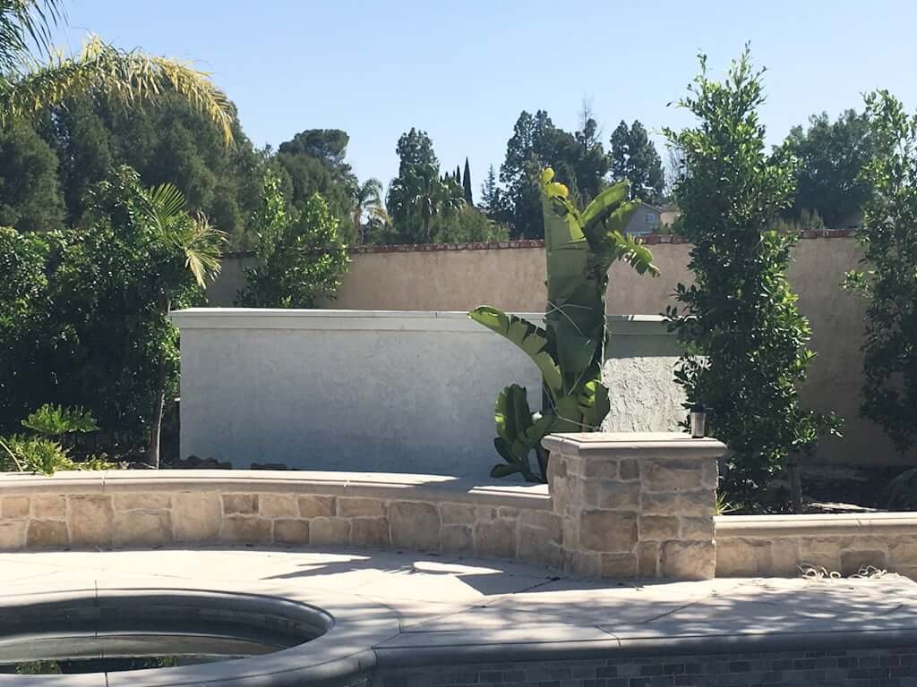 view across pool to DIY outdoor bar with stucco wall and temporary white counter top next to jacuzzi