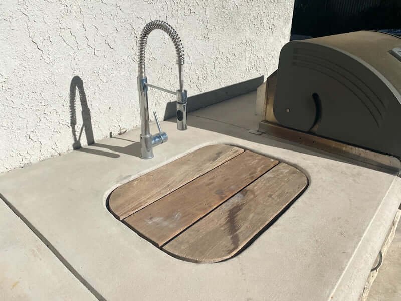 outdoor sink cover made of wood, with concrete countertops and stainless steel sink faucet