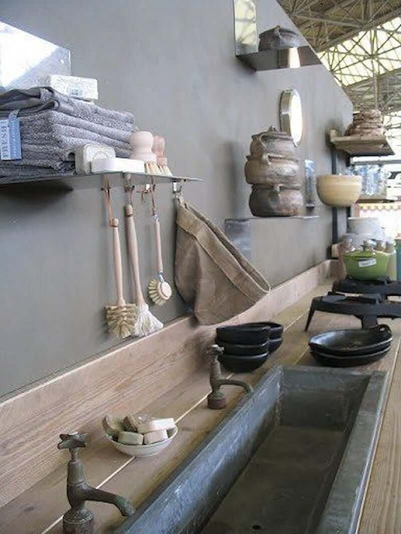 outdoor kitchen sink narrow made of stone with double faucets and kitchen utensils hanging on wall above