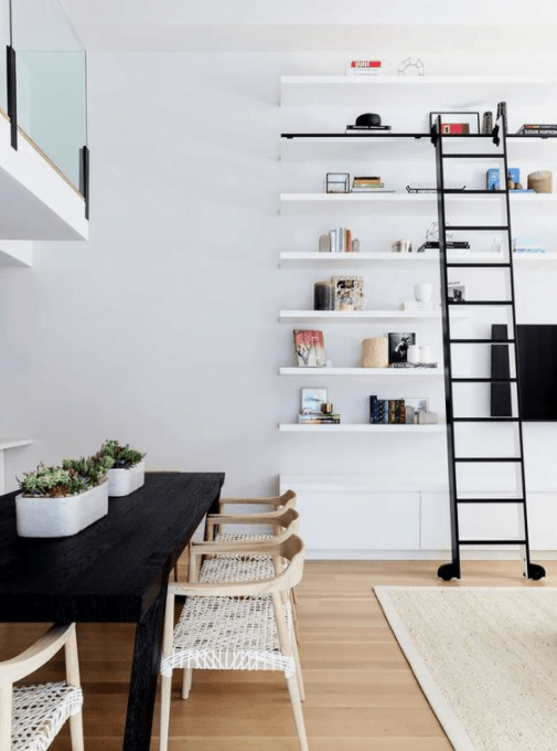 dining room with white walls open bookshelves and black library rolling ladder