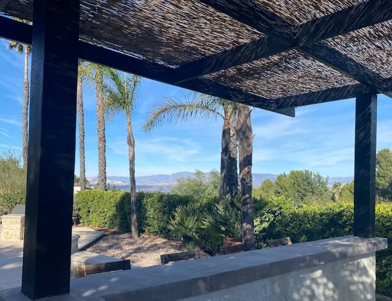 view from outdoor bar with concrete countertops next to pool with mountains in distance