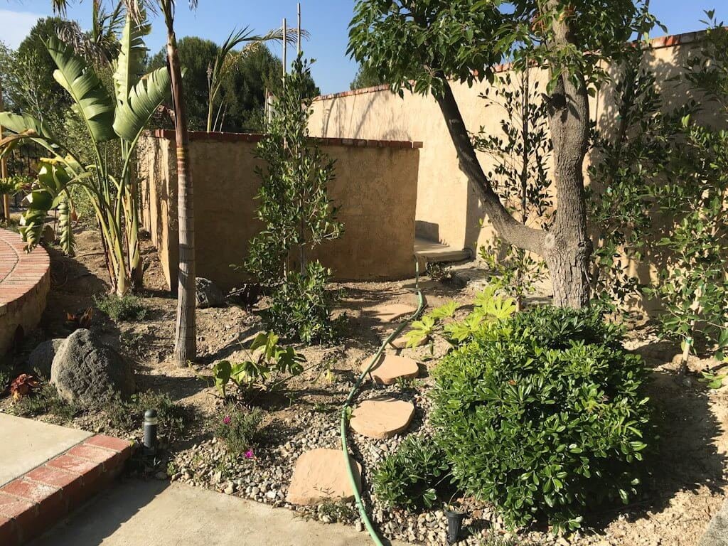 stucco pool equipment wall with landscaping and stepping stones