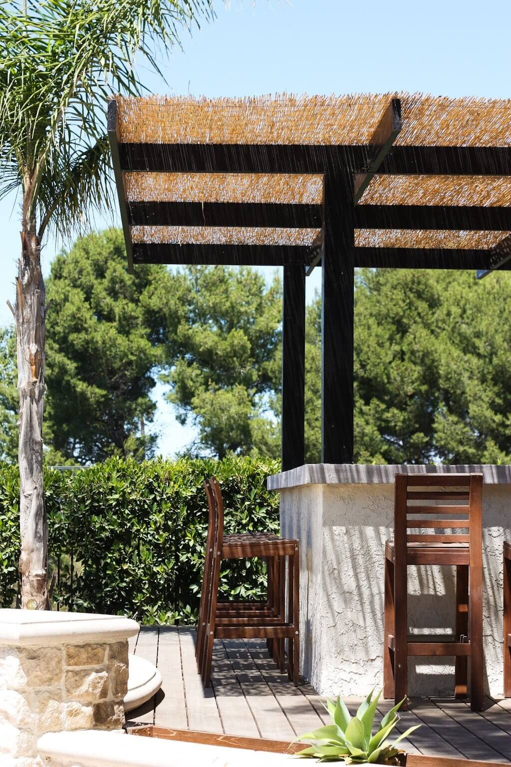 hiding pool equipment with an outdoor bar on deck with stucco wall, concrete countertops, and pergola cover