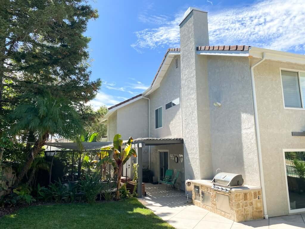 two story house with in-ground trampoline in side yard and outdoor kitchen with sink and BBQ