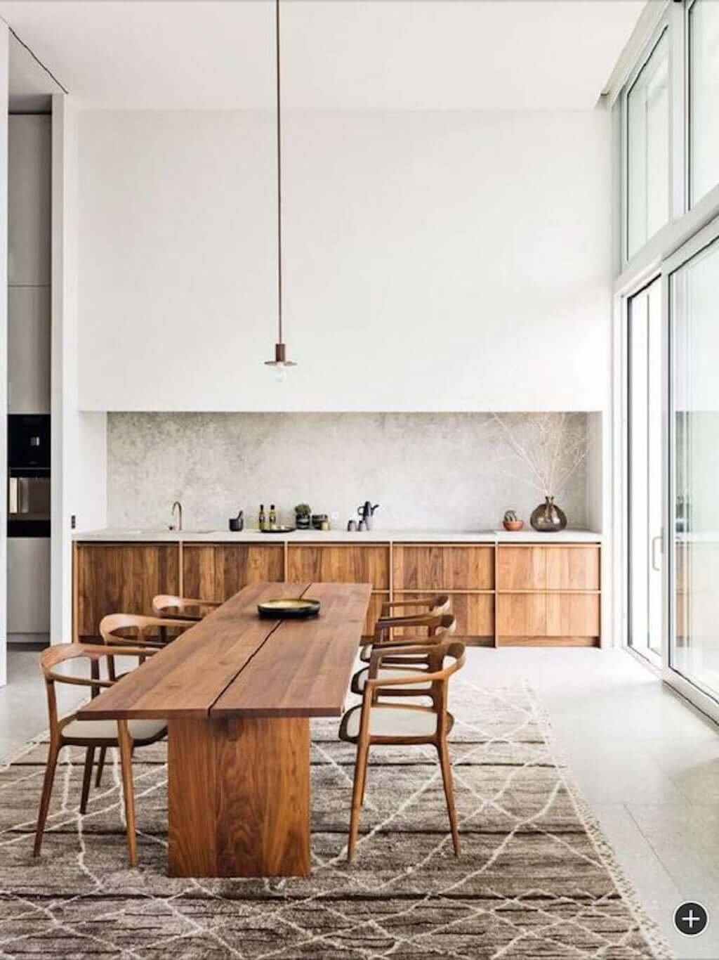 simple minimalist kitchen with wood drawers, wood dining table, and high ceilings