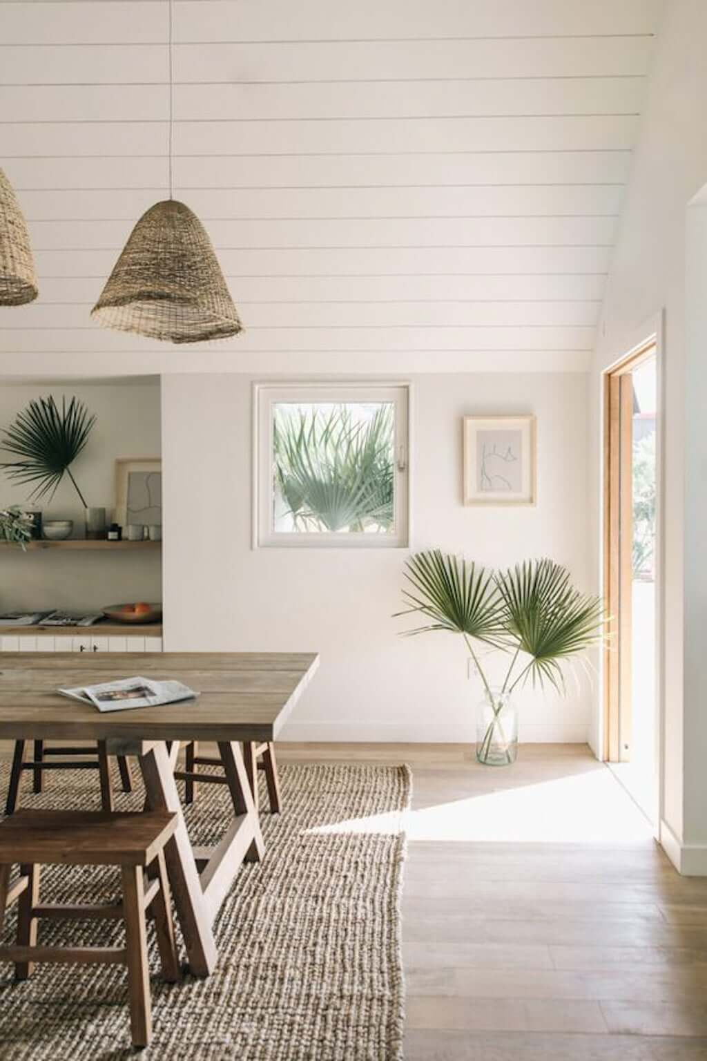 dining room with wood dining table and chairs, woven pendants, and white painted wood paneled ceilings