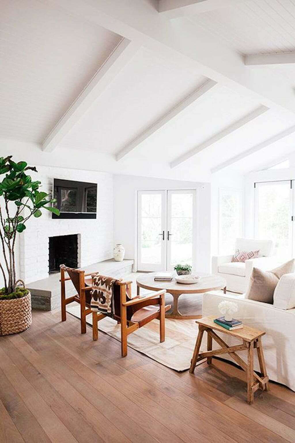 white living room with tall ceilings and wood floors, wood chairs and end table with light couch