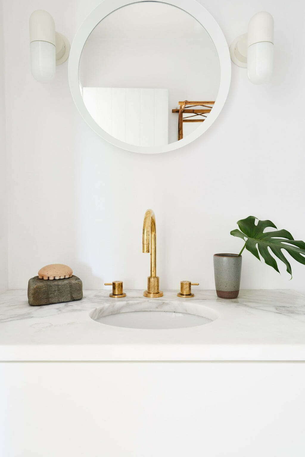 white bathroom with brass faucet and marble countertop