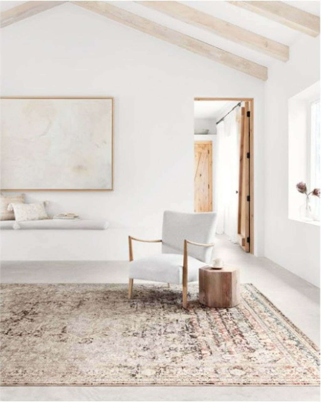 white simple modern beach house living room with chair on rug and wood beams on ceiling