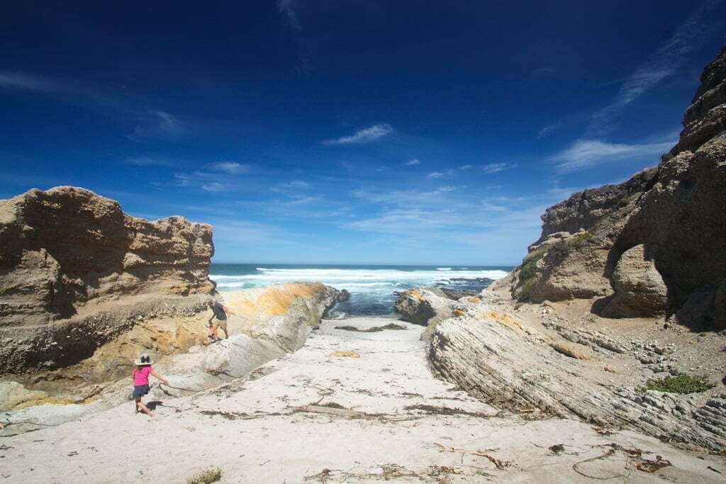 small Montana de Oro beach with rocks on each side and family playing