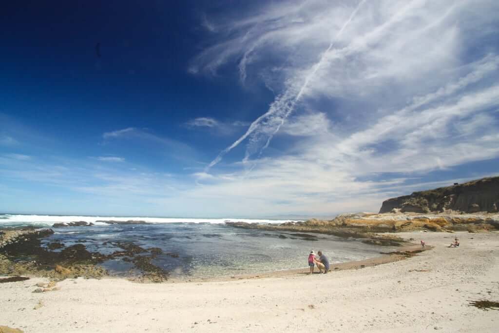 Montana de Oro beach with white sand and ocean cove with father and daughter in foreground