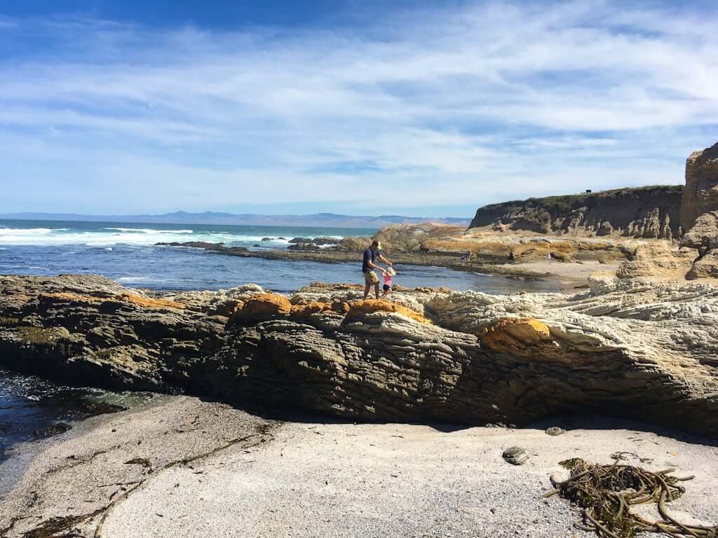 father and daughter climbing on rocks near Montana de Oro beach area