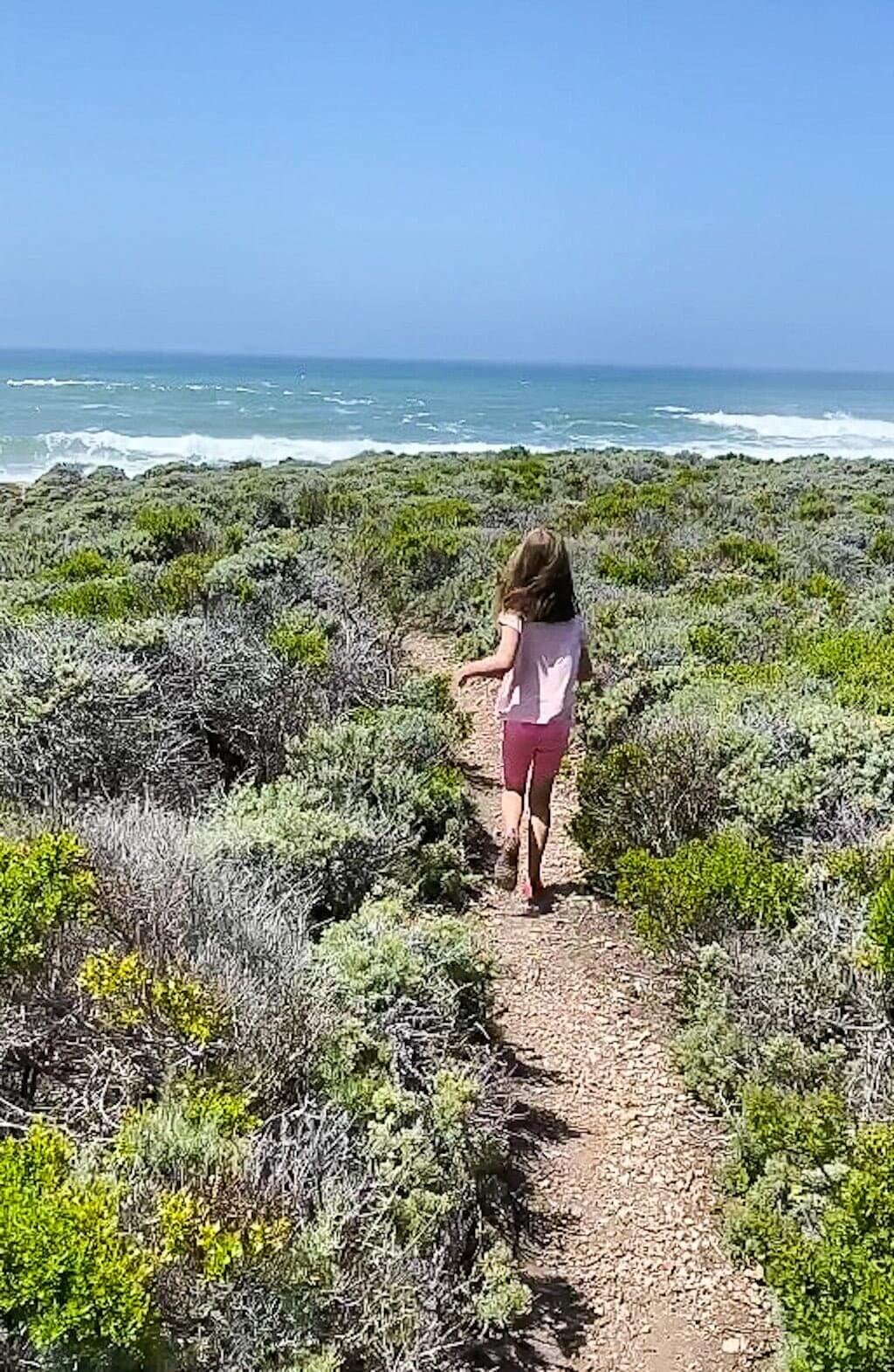 girl running down Montana de Oro trail with ocean in distance