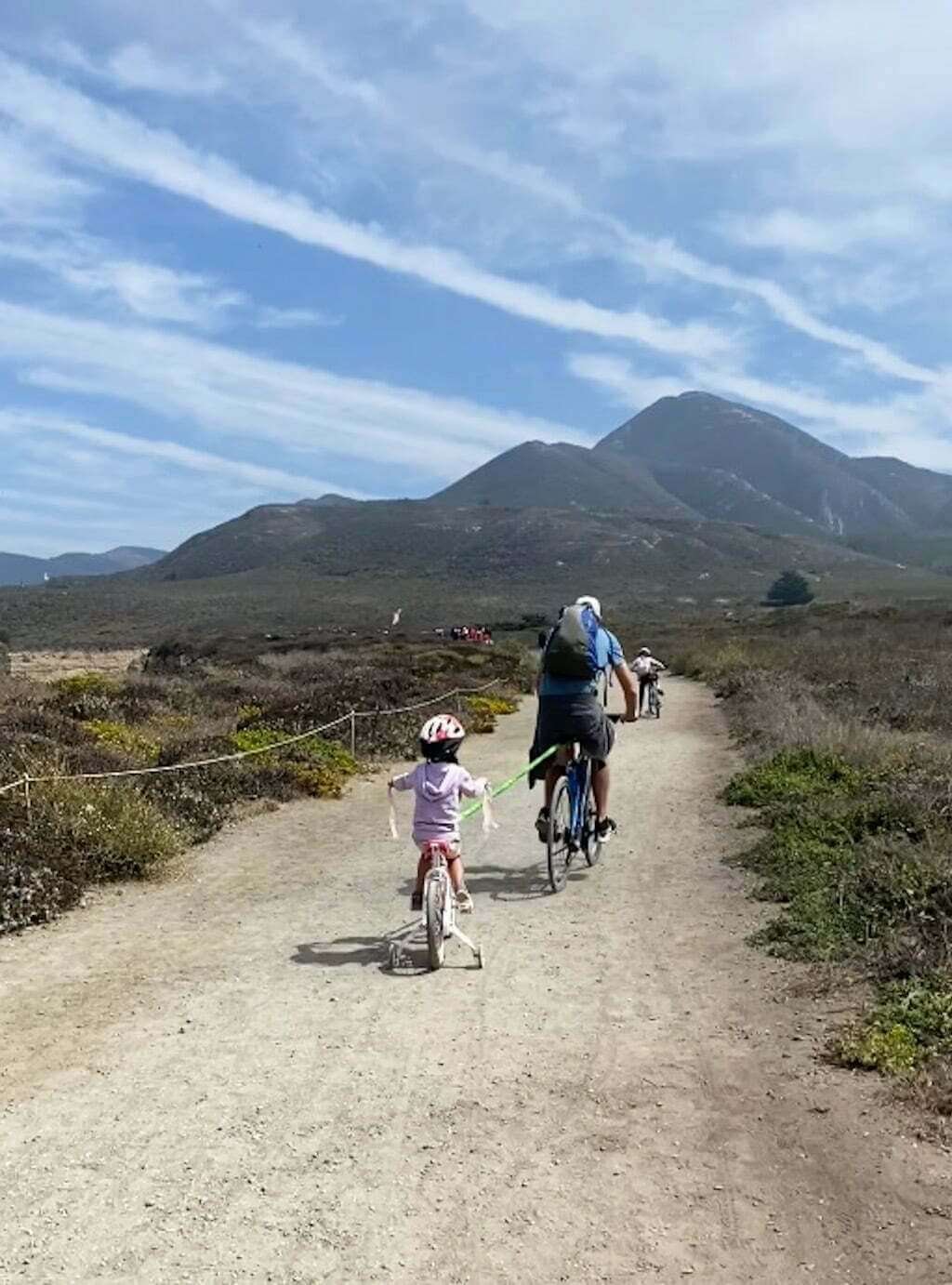 man on bike trail towing child with bike bungee cord